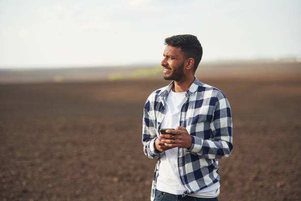 istock Smartphone in hands. Cultivated agricultural field. Handsome Indian man 1497867062