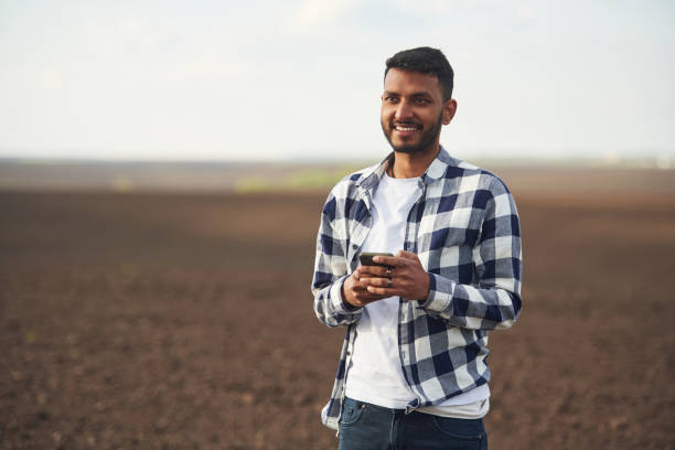istock Smartphone in hands. Cultivated agricultural field. Handsome Indian man 1497867064