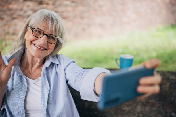 istock Senior woman drinking coffee and using smartphone in the backyard 1497867231