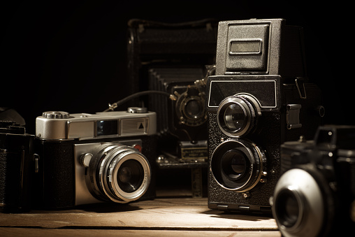 Close up of a group of antique film cameras on a wooden table