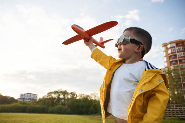 istock Red colored toy plane. Little boy is playing on the summer field 1497868786