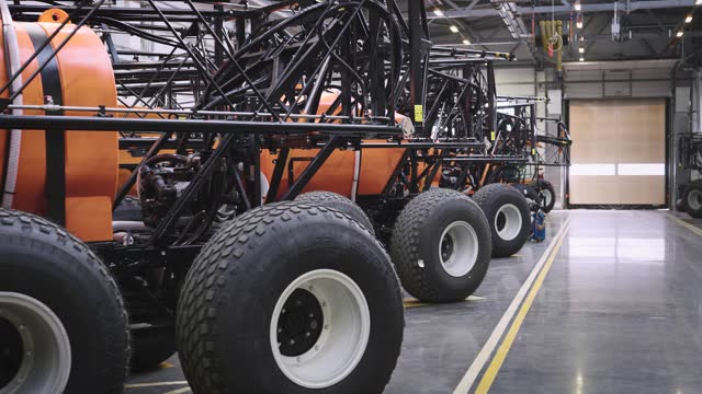 A hangar in which new agricultural machinery is stored. Several low-pressure wheeled vehicles with off-road capabilities are present, prepared for the upcoming season
