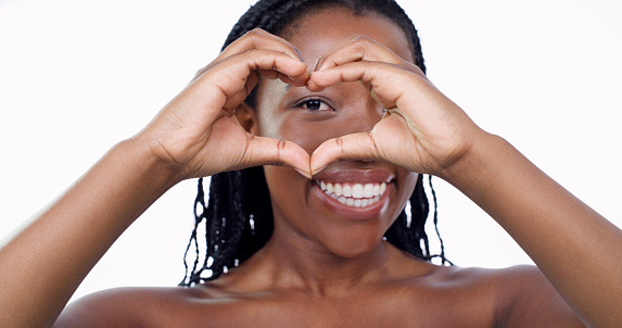 Heart, eye and hands with portrait of black woman in studio for happiness, support and emoji. Peace, love and shape with female person on white background for care, kindness and trust