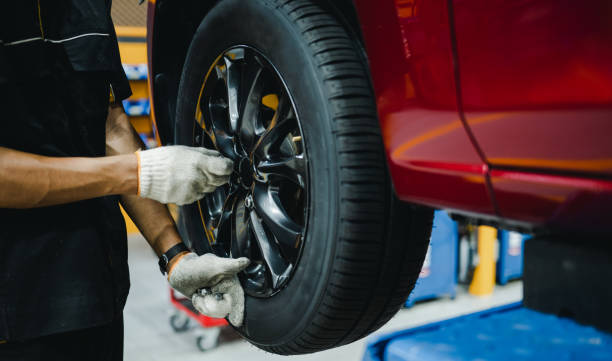 istock Mechanic with screwdriver repairing car wheel in workshop. Hands replace tires on wheels. 1497872612
