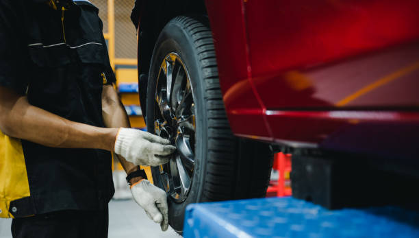 istock Mechanic with screwdriver repairing car wheel in workshop. Hands replace tires on wheels. 1497872613