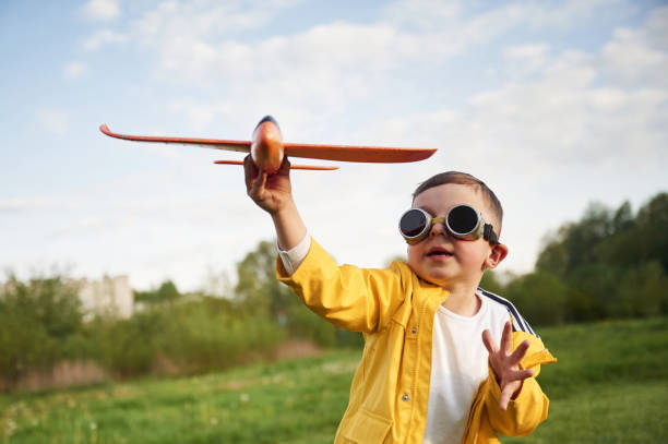 istock Little boy is playing with toy plane on the summer field 1497873088