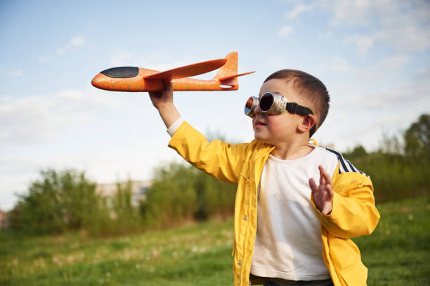 istock Little boy is playing with toy plane on the summer field 1497873675