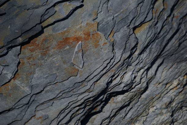 A close-up view of a grey, chiseled stone, with a smooth, polished surface