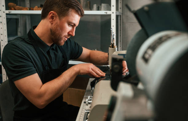 istock View from the side. Working by sewing machine. Man in black shirt is indoors 1497877834