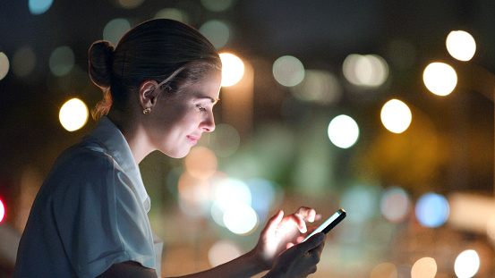 City lights,woman and smartphone for social media scroll, post and global networking on mobile app. Person on phone or cellphone in night bokeh for online chat, web 3.0 or internet