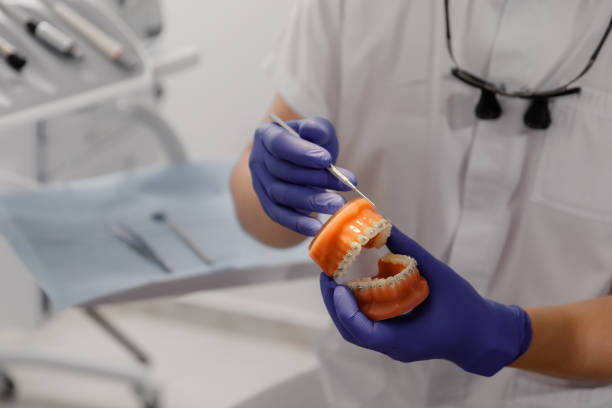 istock Good looking man dentist with protective mask explains to the patient the process of work he using a tooth model for showing and explain easier 1497880075