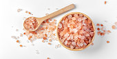 Himalayan pink salt in wooden bowl with spoon on white background