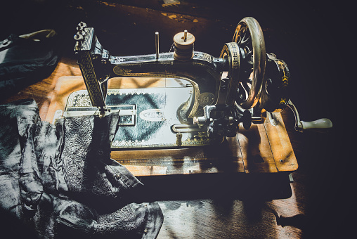 Hand cranked vintage sewing machine sunlit on a work table.
