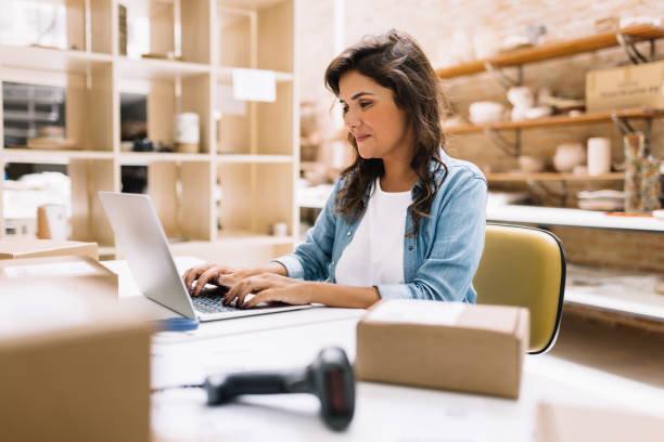 istock Cheerful online store owner using a laptop in a warehouse 1497885147