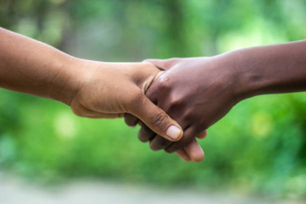 istock Two friends are hand-shaking, one with white hands and the other with black hands. 1497885482