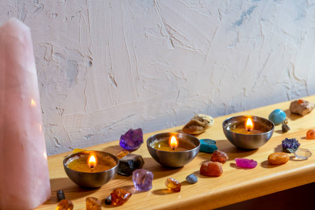 istock Precious and semi-precious gemstones, rose quartz obelisk (or tower) with burning candles on a shelf 1497887756