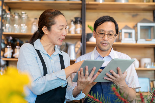 Teamwork helps to analyze root cause problem and keep the business running. Home decoration shop manager with apron holding digital tablet and discuss with senior advisor in the furniture shop. Prepare the best answer to customer.