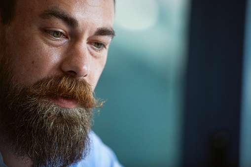 Closeup of a businessman with beard sitting and listening in on business meeting