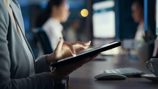 istock Business woman typing on a tablet for research, sending emails or browsing the internet while working late at night in an office. Closeup of hands of a corporate professional scrolling to find data 1497891442