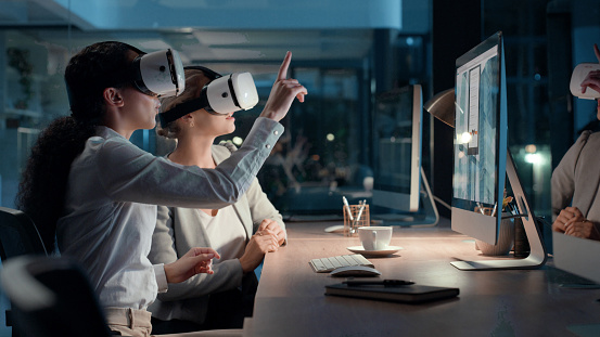 Woman in tech using VR equipment in a modern workplace. Digital business, and professional female workers collaborating and discussing virtual reality. Futuristic, 3D, and metaverse workplace.