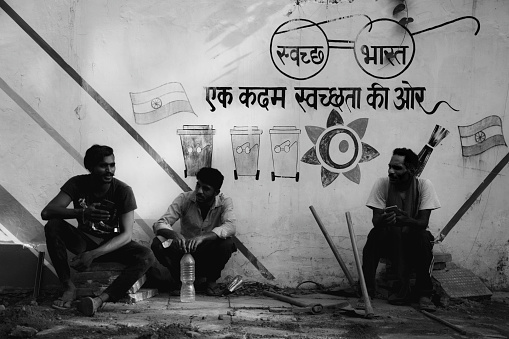 three people on a break while cleaning and constructing a new site on the road. three Gandhiji's spectacles for each person. showing poverty among laborers in India