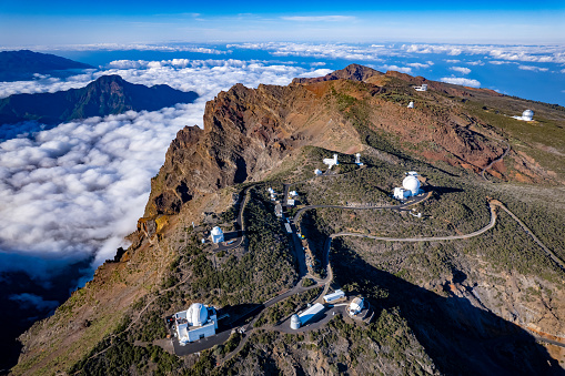 Large telescope at summit of mountain above the clouds
