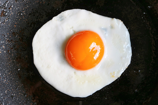 Top view of a sunny side up egg being fried in a pan