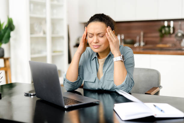 istock Frustrated young woman using laptop computer suffering from headache, sitting in home office and holding head with hands, feels sick and unwell 1497900222