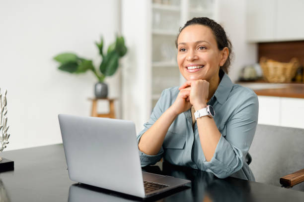 istock Smiling business woman using laptop for remote work from home. Confident lady checking emails, conducting business correspondence while sitting at the table 1497900250