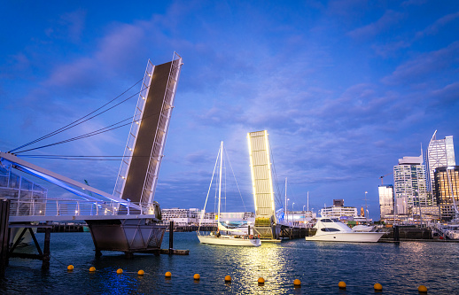 The modern footbridge spanning Auckland's viaduct harbour open to allow a yacht to head out into Waitemata Harbour