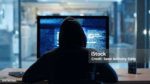 Back Of Hacker Or Cyber Criminal Stealing Information Online Sitting At A Computer At Night Hooded Mysterious Person Coding Spyware Malware And Viruses To Commit Fraud Theft And Phishing Scam Stock Photo - Download Image Now