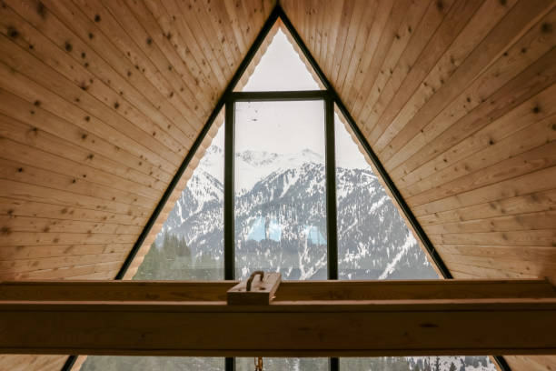 Old wooden ski leaning at the shingled wall of a cabin. There are icicles at the roof and snow on the ground.