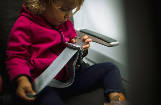 A young girl buckles her seat belt in an airplane