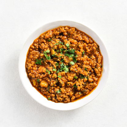 Keema curry in bowl over white stone background. Indian and pakistani style dish. Top view, flat lay