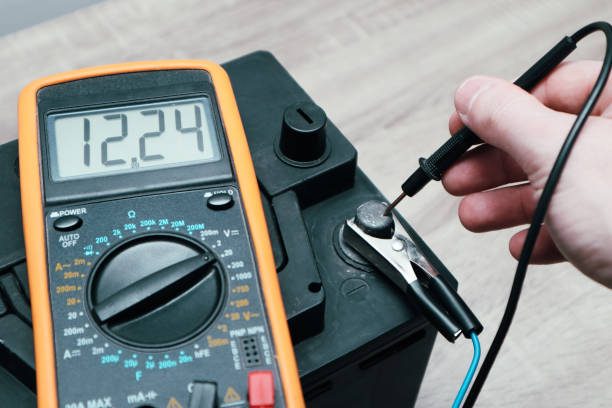 istock Check and charge car battery with charger. Auto mechanic measures voltage. Voltmeter to check voltage level on car battery. Car battery maintenance - 12v, low battery 1497910411