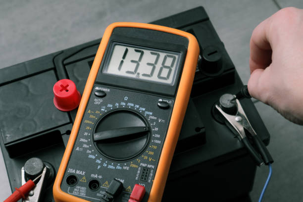 istock Check and charge car battery with charger. Auto mechanic measures voltage. Voltmeter to check voltage level on car battery. Car battery maintenance - 12v, low battery 1497910412
