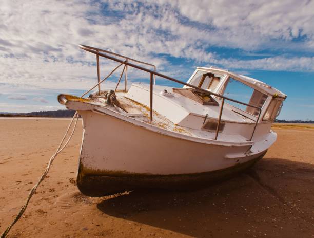 A white sailing boat beached on a sandy shoreline