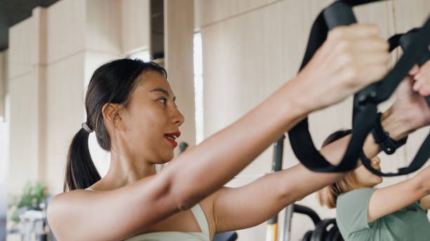 istock Young Asian athletic sports women exercise bodybuilder pulling down wire cable actively training in modern gym. Sports people workout. 1497912466