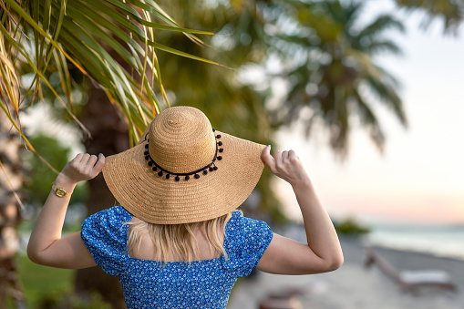 Back view of a woman in a straw hat on the beach on vacation
