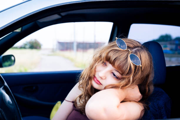 Drunk and sad female driver sleeping behind the wheel stock photo