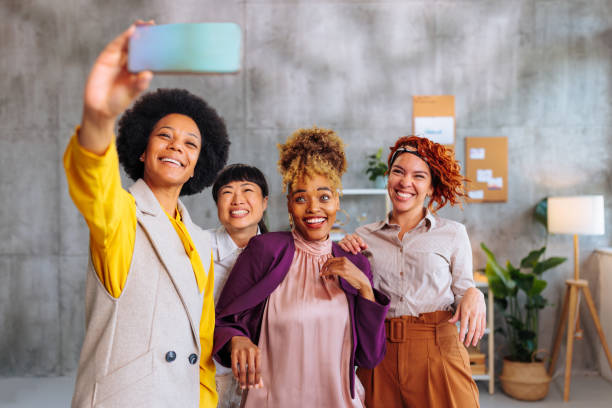 istock Four multiracial business women taking group selfie while working in office. 1497916670