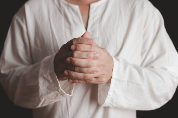 istock An adult whose hand is prayed on the dark background.Respect for belief in religion and God. front view. peace concept. 1497917095