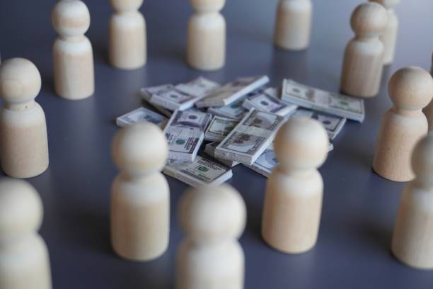 istock Group of wooden dolls and stack of money. 1497917478