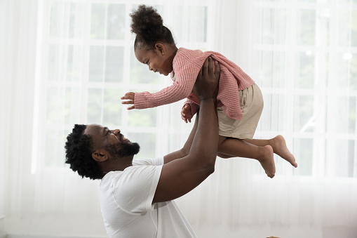 Father and daughter playing together at home. Happy African American little girl kid playing with dad. Happy African American family spending time together