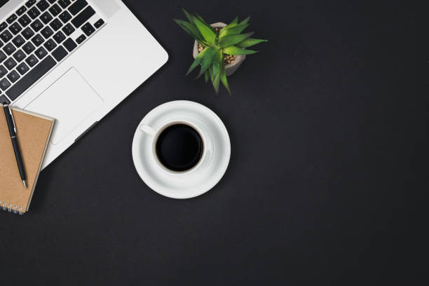 istock Laptop, notepad and cup of black coffee on black background, top view. 1497921797