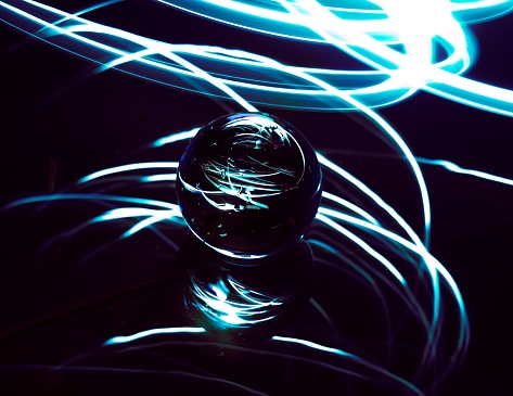 A high-resolution image of a glass marble illuminated by a shimmering light