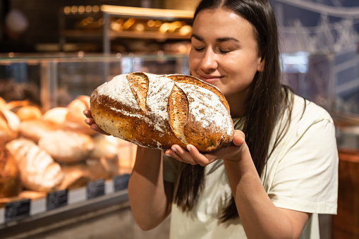 A woman smells the smell of freshly baked bread in a bakery.