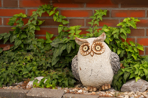 Stone owl in a flower bed. Original garden figure and decoration