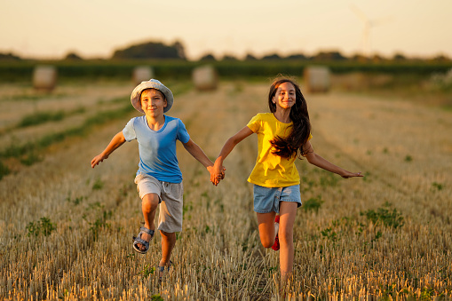 A couple of teenagers in love running across a summer field