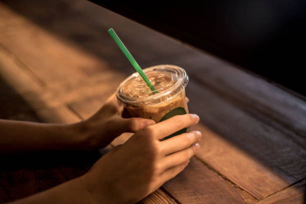 istock Warm Morning Brew: Coffee Hands Holding a Cup on Sunlit Wooden Table 1497929906